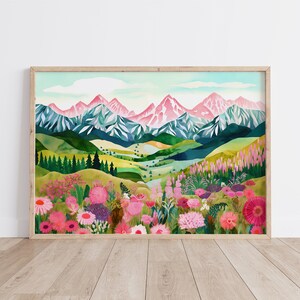 May include: A watercolor painting of a mountain range with pink peaks and a valley filled with wildflowers. The mountains are in the background and the wildflowers are in the foreground. The painting is framed in a light wood frame.