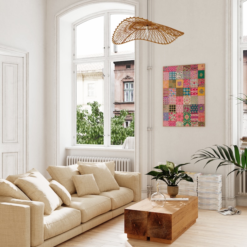 May include: A beige sofa with multiple pillows in a living room with a large window, a wooden coffee table, a woven pendant light, and a colorful patchwork wall art.