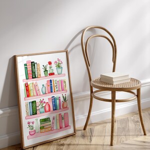 May include: A framed watercolor illustration of a bookshelf filled with colorful books and potted plants. The bookshelf has four shelves and is painted in a light pink color. The books are arranged in a random order and are of different sizes and colors. The plants are green and have pink flowers.