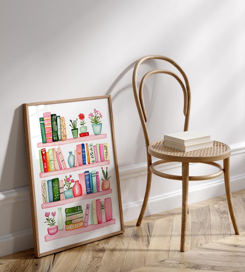 May include: A framed watercolor illustration of a bookshelf filled with colorful books and potted plants. The bookshelf has four shelves and is painted in a light pink color. The books are arranged in a random order and are of different sizes and colors. The plants are green and have pink flowers.