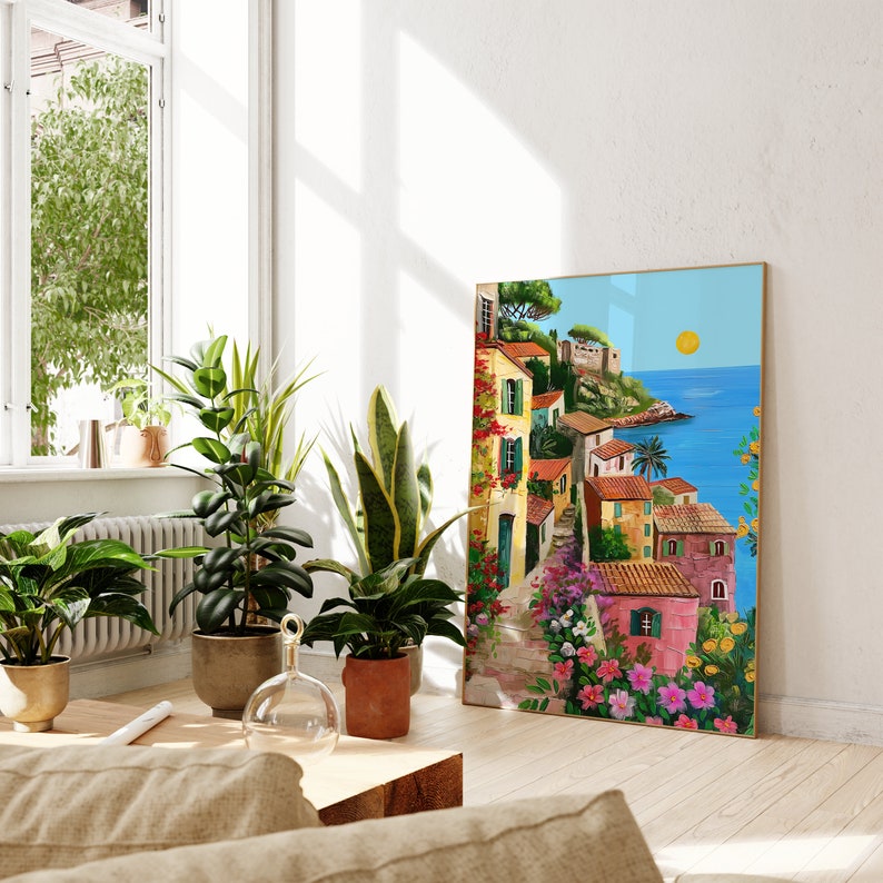 May include: A colorful painting of a seaside town with buildings in shades of yellow, pink, and blue. The painting features a bright blue sky with a yellow sun and a view of the ocean. The town is surrounded by lush green trees and flowers.
