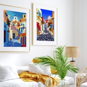 May include: Two framed illustrations of a colorful, narrow street in a Greek village. The street is lined with white buildings with blue accents and features a cobblestone path.