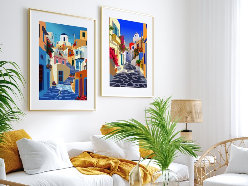 May include: Two framed illustrations of a colorful, narrow street in a Greek village. The street is lined with white buildings with blue accents and features a cobblestone path.