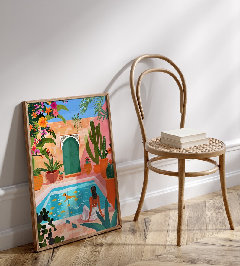 May include: A framed illustration of a woman sitting by a pool in a courtyard with a green door, cacti, and flowers. The pool is blue and the woman is wearing a white dress. The illustration is in a colorful style.