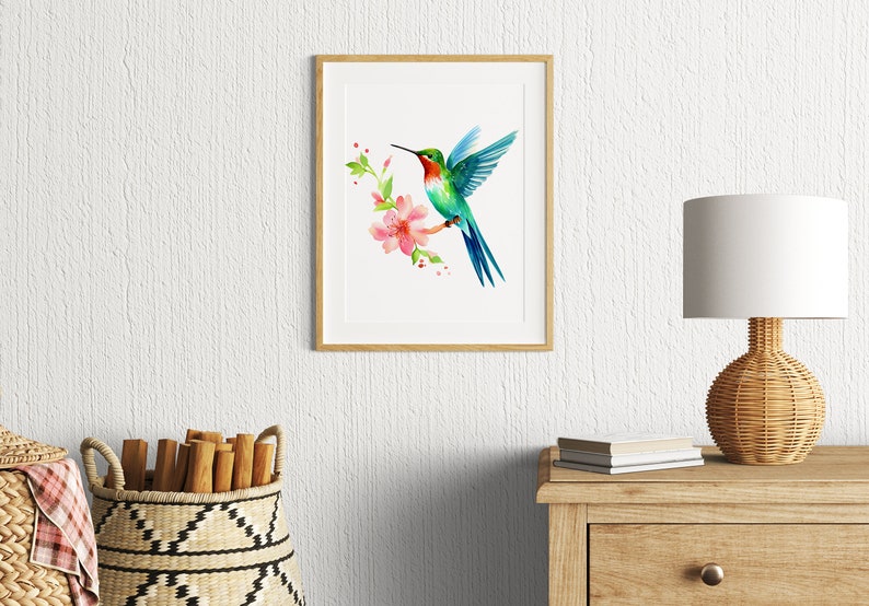 Puede incluir: Una pintura de acuarela enmarcada de un colibr&iacute; en vuelo, con una flor rosa y hojas verdes. El colibr&iacute; es azul, verde y rojo.