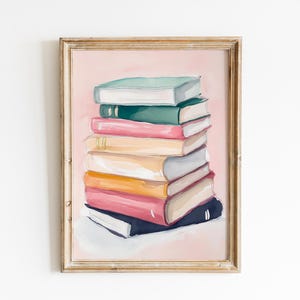 May include: A framed painting of a stack of colorful books on a pink background. The books are arranged in a neat pile, with the top book being a light green color. The painting is in a simple wooden frame.