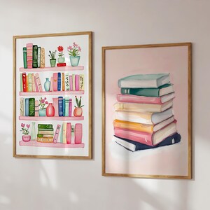 May include: Two framed watercolor paintings of books. The first painting shows a pink bookshelf with colorful books, plants, and vases. The second painting shows a stack of colorful books on a pink background.