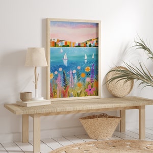 May include: A framed painting of a colorful cityscape with sailboats on a blue body of water. The foreground features a field of bright flowers in shades of pink, purple, yellow, and orange.