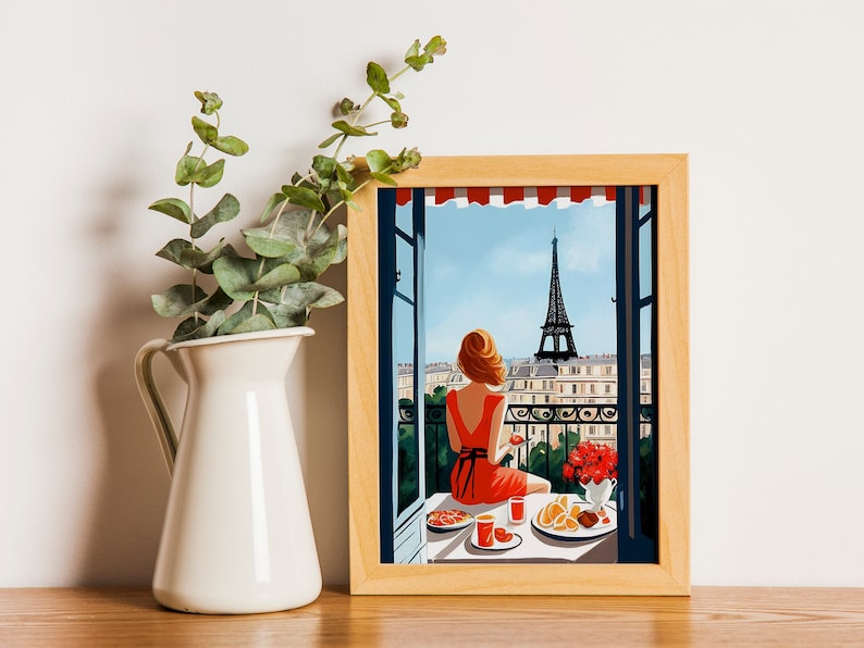 Pode incluir: Uma ilustra&ccedil;&atilde;o emoldurada de uma mulher sentada em uma varanda com vista para a Torre Eiffel em Paris, Fran&ccedil;a. Ela est&aacute; vestindo um vestido vermelho e desfrutando de uma refei&ccedil;&atilde;o com um copo de suco. A varanda &eacute; decorada com flores e vegeta&ccedil;&atilde;o.
