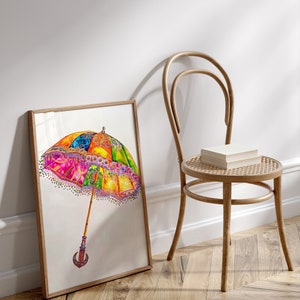 Op de afbeelding: Een ingelijst aquarel schilderij van een kleurrijke, gepatroneerde paraplu met een houten handvat. De paraplu is afgebeeld tegen een witte achtergrond.