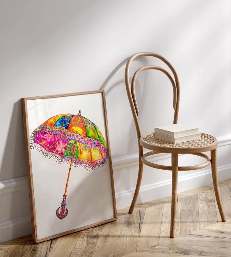 Op de afbeelding: Een ingelijst aquarel schilderij van een kleurrijke, gepatroneerde paraplu met een houten handvat. De paraplu is afgebeeld tegen een witte achtergrond.