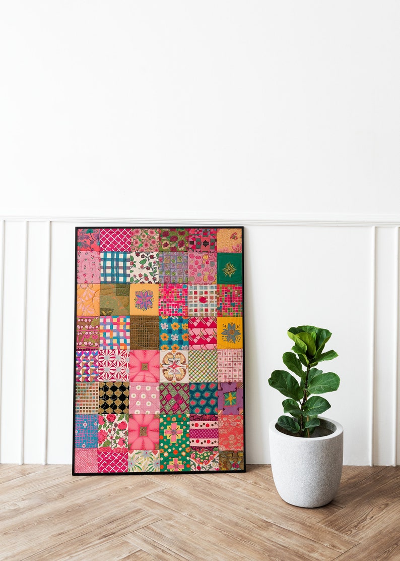 May include: A framed artwork featuring a colorful patchwork quilt design with various patterns and colors, including pink, green, yellow, and blue. The artwork is displayed on a wooden floor with a potted plant in the foreground.