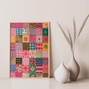 May include: A framed print of a colorful patchwork quilt design with various patterns and colors, including pink, green, yellow, and blue. The print is framed in a light wood frame and is displayed on a white wall.