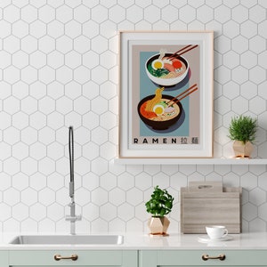Pode incluir: Um p&ocirc;ster emoldurado com um design minimalista que apresenta duas tigelas de macarr&atilde;o ramen. O p&ocirc;ster tem um fundo azul claro com o texto "RAMEN 拉麺" na parte inferior.