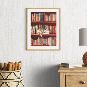 May include: A framed illustration of a cat sleeping on a bookshelf filled with colorful books. The cat is curled up on the top shelf, with its head resting on a book. The bookshelf is made of wood and has a red background.