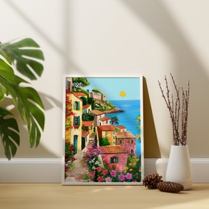May include: A framed painting of a colorful seaside village with houses, a winding path, and lush greenery. The ocean is visible in the background with a bright yellow sun.