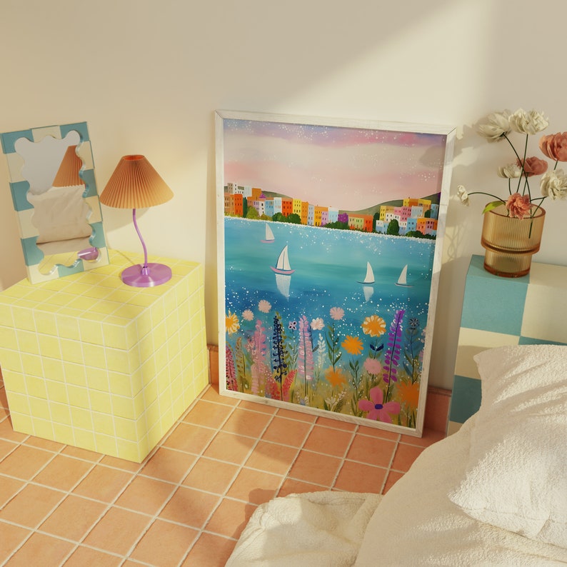May include: A framed painting of a colorful cityscape with sailboats on a blue body of water. The cityscape is in the background and the foreground features a field of flowers in shades of pink, purple, yellow, and blue.