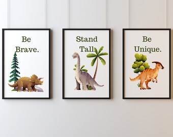 May include: Three framed prints with dinosaur illustrations and motivational messages. The first print features a brown triceratops with a green tree and the text "Be Brave.". The second print features a gray brachiosaurus with a palm tree and the text "Stand Tall.". The third print features an orange dinosaur with a green bush and the text "Be Unique."
