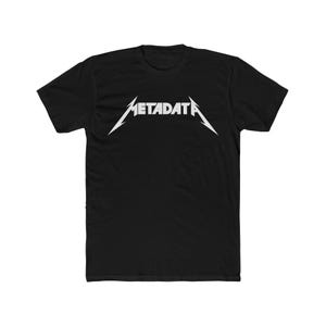 May include: Black t-shirt with the word "METADATA" in white, stylized in a sharp, angular font. The design is centered on the chest of the shirt. The t-shirt is a short-sleeved crew neck.