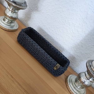 Könnte beinhalten: Ein rechteckiger grauer Strickkorb mit einem kleinen braunen Etikett mit der Aufschrift "Hello from the Maker".