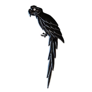 May include: A black parrot-shaped brooch with a glossy finish. The bird is perched, with a long, detailed tail and a small, sparkling accent on its head. The brooch is a decorative accessory.