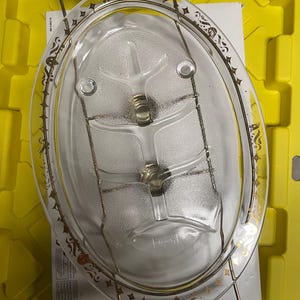 May include: A clear glass serving dish with a gold rim and a decorative pattern. The dish has a built-in divider for serving multiple items. The dish is on a metal stand with wooden handles.