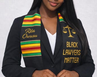 Geborduurde afstudeersjerp, Kente-stal uit 2026, Black Lawyers Matter, symbool van Vrouwe Justitia, stal rechtenstudie,