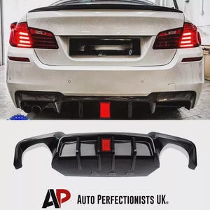 May include: The rear of a white car with a black aftermarket diffuser and a red central light. The diffuser is shown fitted and separately. The text "AP AUTO PERFECTIONISTS UK." is visible.