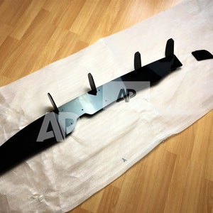 May include: Black car spoiler with five vertical fins. The spoiler is made of a glossy material and has a sleek design.