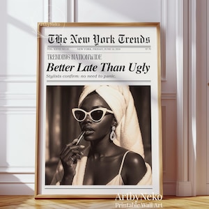 May include: A framed sepia-toned print featuring a woman applying lipstick, wearing sunglasses and a towel. The print is designed to look like a newspaper, with the headline "Better Late Than Ugly."