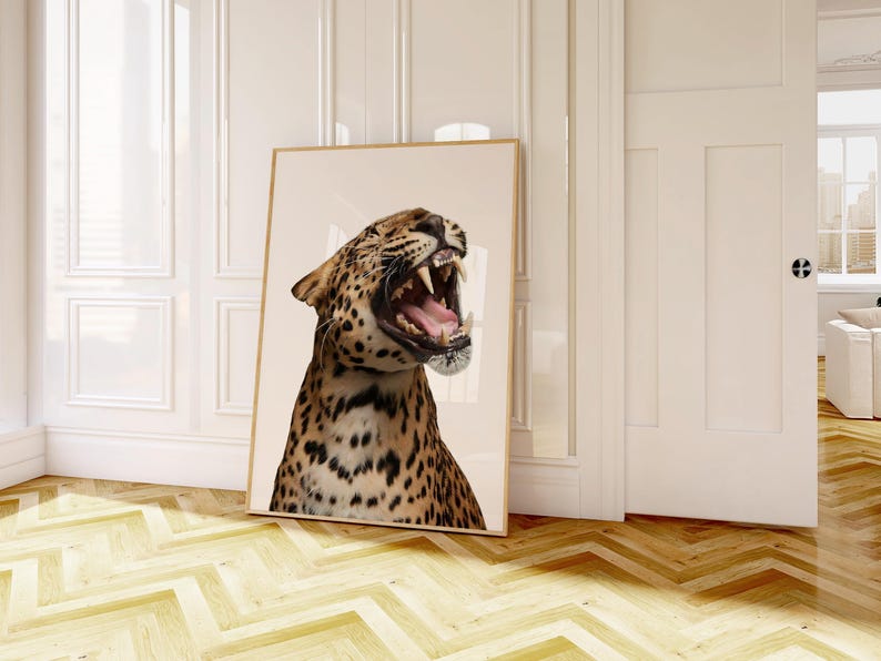 May include: A framed print of a roaring leopard, with its mouth wide open. The leopard's fur is tan with black spots. The artwork is displayed against a neutral background. The print is leaning against a white wall.