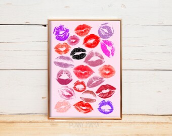 May include: A framed print featuring a collection of lipstick kiss marks in various shades of red, pink, purple, and black on a light pink background. The print is in a gold frame and is a decorative piece.