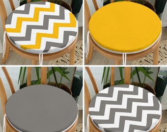 May include: Four round chair cushions in a variety of colors and patterns. One cushion has a yellow, white, and gray chevron pattern. Another is solid yellow. A third is solid gray, and the last has a white and gray chevron pattern.