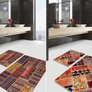 May include: Two rectangular bath mats featuring a patchwork design of various woven textile patterns in shades of red, orange, brown, blue, and cream. The mats have a low-profile construction with finished edges and a multi-colored geometric aesthetic.