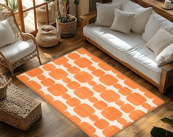 May include: Orange and white geometric patterned area rug with a modern design. The rug is laid out on a wooden floor in a living room setting.