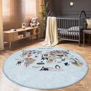 May include: A round, light blue rug with a world map design featuring animal illustrations. The rug has a light blue border and the words "ANIMAL WORLD" are printed at the top. The rug is placed on a wooden floor.