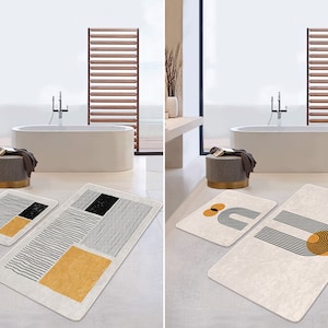 Könnte beinhalten: Zwei Sets Badezimmerteppiche mit abstrakten geometrischen Mustern. Ein Set zeigt schwarze und weiße Linien mit einem gelben Rechteck. Das andere Set zeigt schwarze und weiße Linien mit einem gelben Kreis und einem schwarzen Bogen.