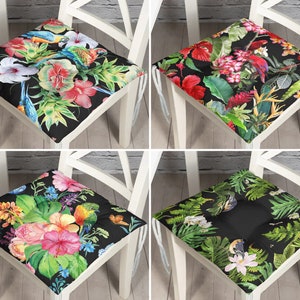 May include: Four black and white chair cushions with tropical floral and bird patterns. The cushions feature vibrant colors like red, pink, green, and blue.
