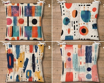 Puede incluir: Cuatro cojines de silla diferentes con formas geométricas y diseños abstractos en tonos de azul, rojo, naranja, amarillo y negro sobre un fondo blanco. Los cojines están numerados del 1 al 4.