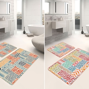 Op de afbeelding: Twee badmatten met een kleurrijk geometrisch patroon in tinten blauw, oranje, rood, groen en geel. De matten zijn gemaakt van een zacht, absorberend materiaal en zijn perfect om elke badkamer een vleugje stijl te geven.
