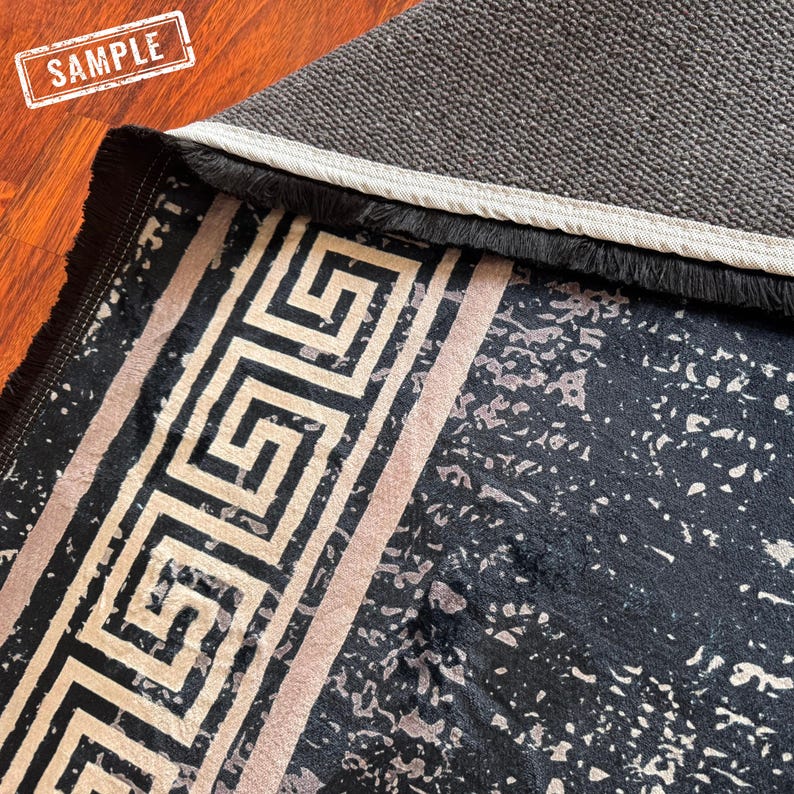 May include: Black and white area rug with a geometric pattern and a fringe border. The rug has a subtle speckled pattern.