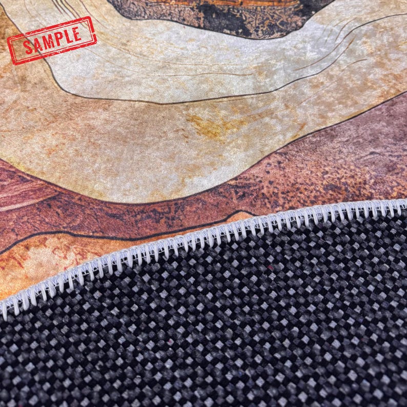 a close-up view of a woven rug or carpet with a black and gray pattern. The rug appears to be made of a textured material, possibly a synthetic fiber, and has a sample of the rug visible in the foreground.