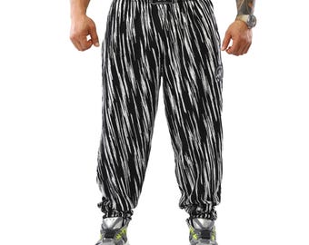 Könnte beinhalten: Schwarz-weiß gestreifte Sporthose mit Kordelzugbund und elastischen Bündchen. Die Hose hat ein kleines Logo am Bund und ein passendes Logo am oberen Oberschenkel. Die Hose wird mit silbernen und grauen Sportschuhen kombiniert.