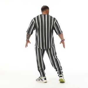 K&ouml;nnte beinhalten: Ein schwarz-wei&szlig; gestreiftes T-Shirt und eine passende Hose. Das Shirt hat einen Rundhalsausschnitt und kurze &Auml;rmel. Die Hose hat eine lockere Passform.