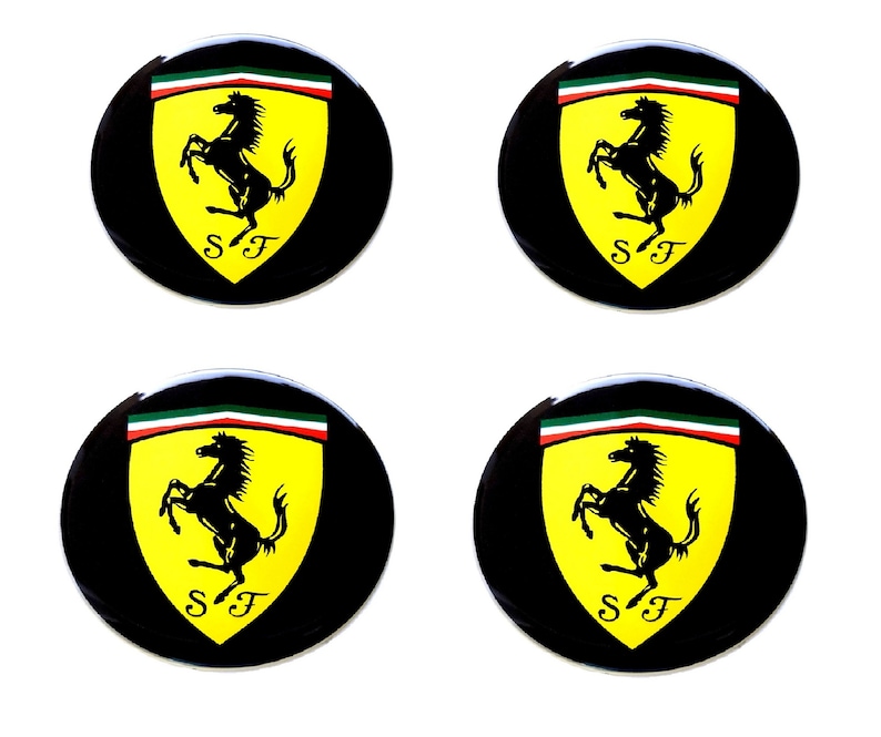 May include: Four black circular emblems featuring the Ferrari logo. Each emblem has a yellow shield with a black prancing horse, the letters "SF" below, and a green, white, and red stripe at the top.