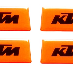 Könnte beinhalten: Vier orangefarbene rechteckige Aufkleber mit dem schwarzen KTM-Logo.