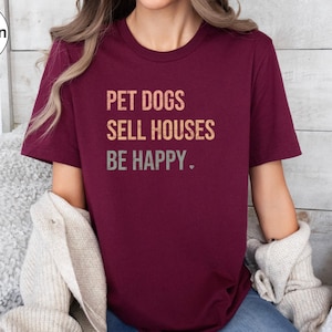 a woman wearing a realtor t - shirt that says pet dogs sell houses be happy