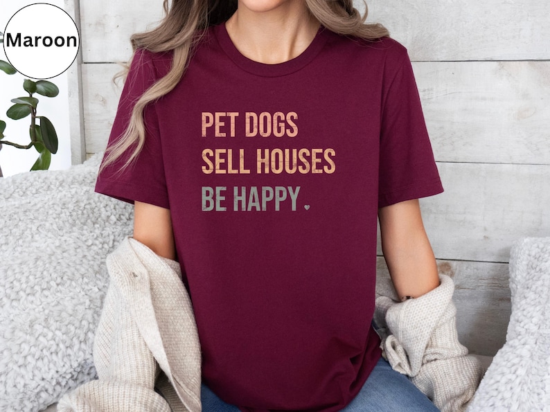 a woman wearing a realtor t - shirt that says pet dogs sell houses be happy