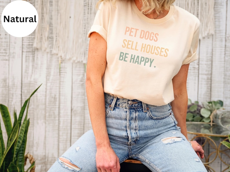 a woman wearing a realtor t - shirt that says pet dogs sell houses be happy
