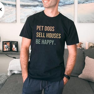 a woman wearing a realtor t - shirt that says pet dogs sell houses be happy